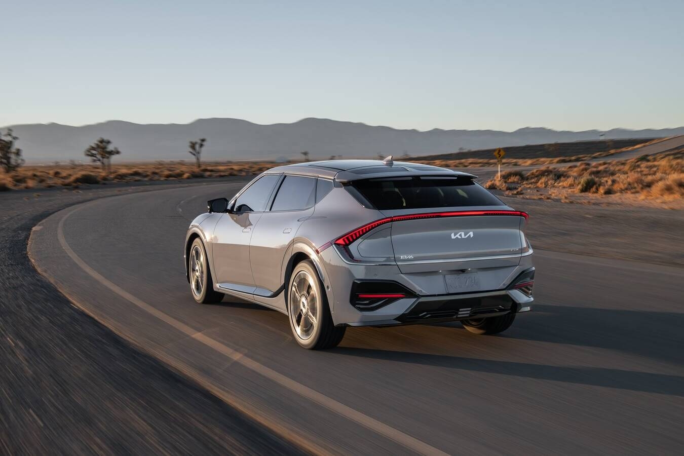 Vue 3/4 arrière du Kia EV6 2025 roulant sur une route.
