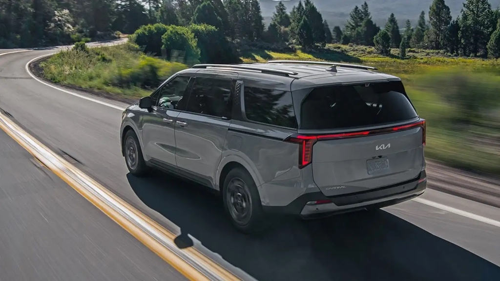 Vue 3/4 arrière du Kia Carnival 2025 roulant sur une route.